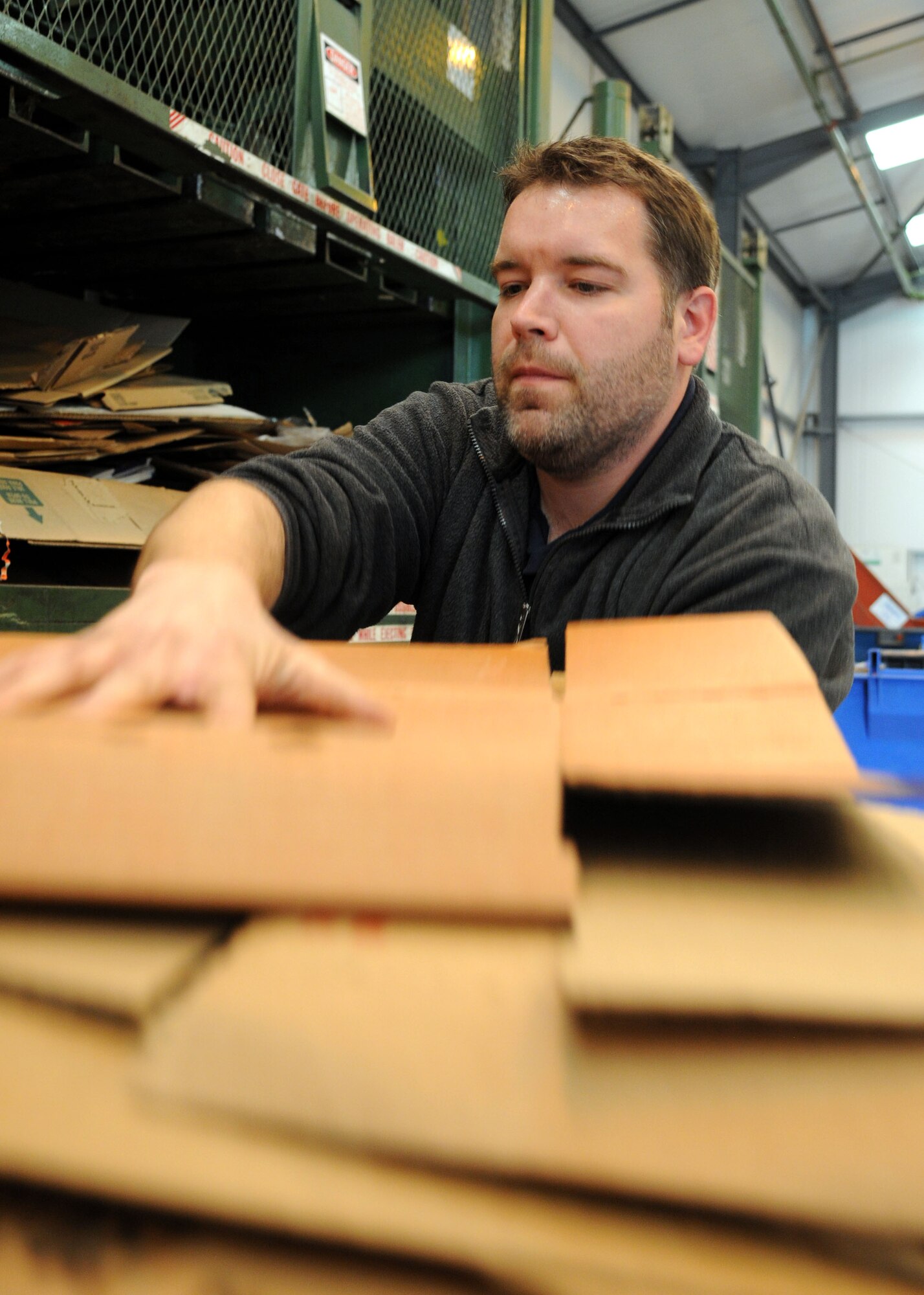 Rory Palmer, 100th Civil Engineer Squadron Recycling Center manager, unloads cardboard from a bin into a cardboard bailer April 17, 2013, at RAF Mildenhall, England.  Last year, the center diverted more than 560 U.S. tons of recycling material from going into on-base dumpsters as solid waste. To increase recycling and reduce landfill waste, base patrons can help by ensuring all recyclable items are properly separated for pickup. (U.S. Air Force photo by Staff Sgt. Tabitha M. Lee/Released)
