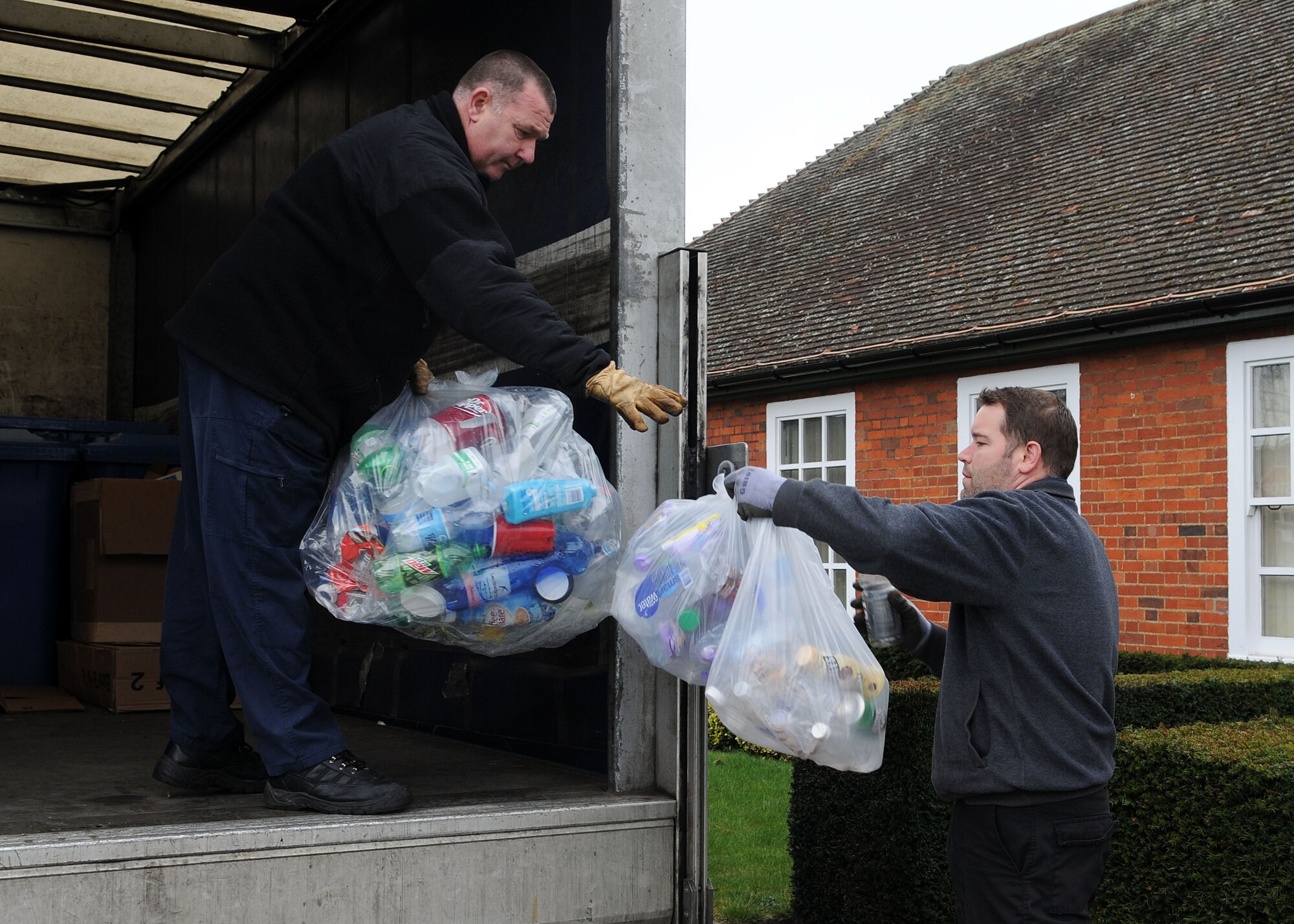 From left, Paul Courtenay, 100th CES environmental materials handler, takes a bag of recyclables from Rory Palmer, 100th Civil Engineer Squadron Recycling Center manager, during a pickup April 17, 2013, at RAF Mildenhall, England.  The recycling center accepts cardboard, plastic, cans, paper, magazines, glass, toner cartridges and scrap metal for recycling. (U.S. Air Force photo by Staff Sgt. Tabitha M. Lee/Released)