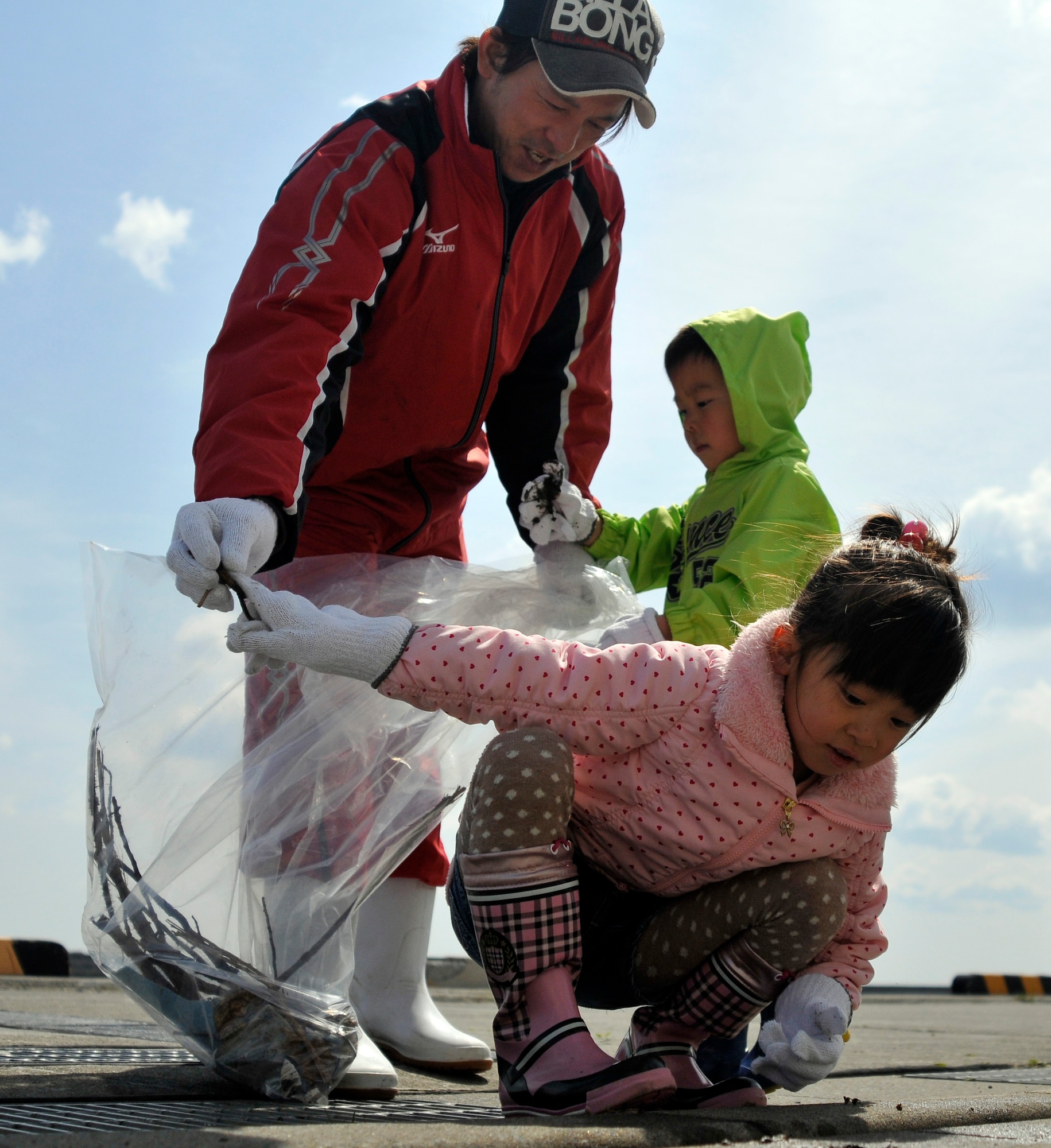 Mireo Tachibana, front, and her brother Haruto pickup trash and place it in the bag their father Hiroshi holds at the 15th Annual Misawa Port Cleanup, April 20, 2013. A mixed group of Japanese and base residents came out to clean the port.  More than 500 volunteers arrived to help remove garbage from the port. (U.S. Air Force photo by Tech. Sgt. Phillip Butterfield)