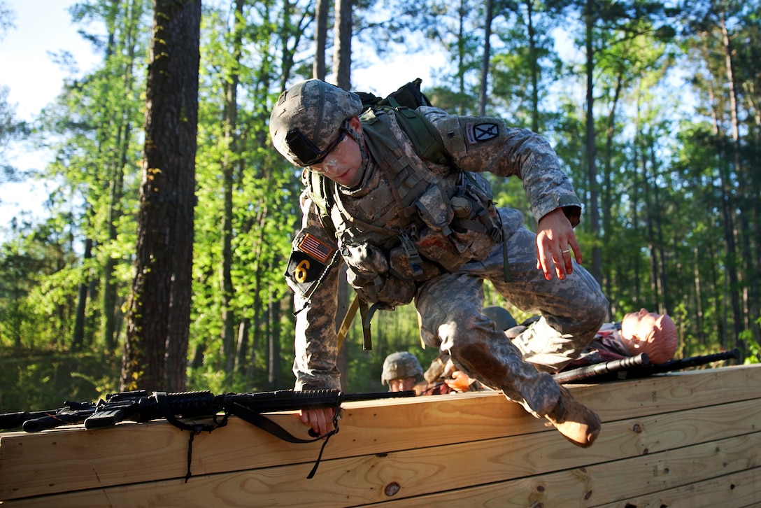 Army Capt. Benjamin Hartig jumps over a 6-foot wall before moving a ...