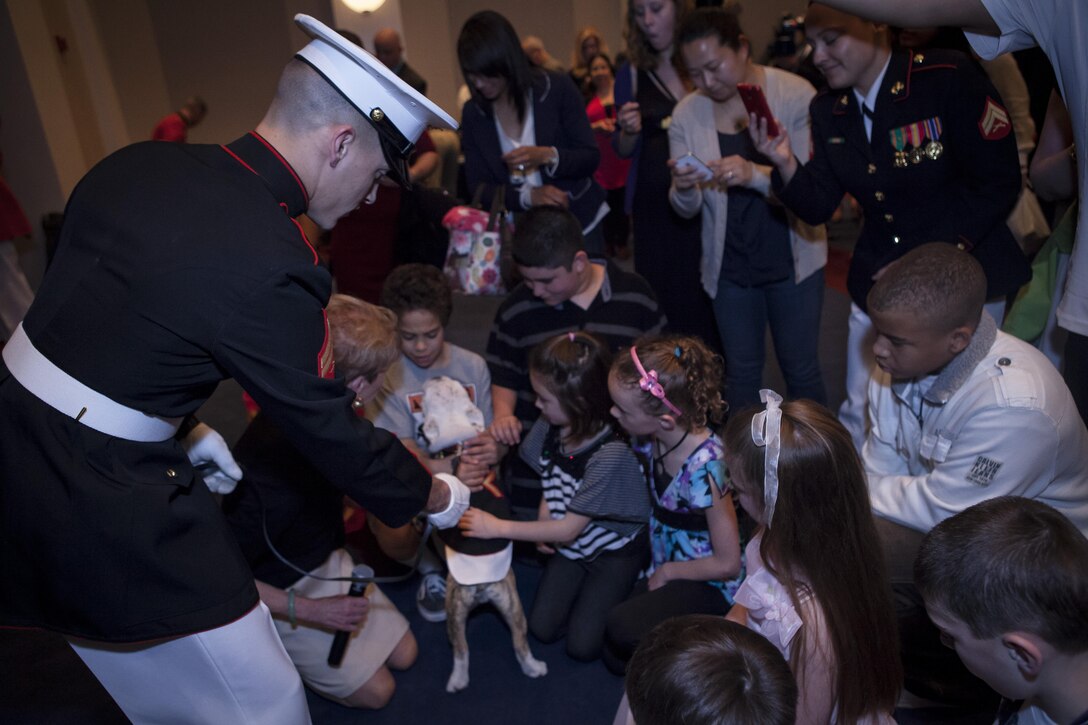 Cpl. Gaige Roberts, the official mascot of the Marine Corps in-training handler, maneuvers Chesty XIV around a crowd of guest prior to the commencement of a Family Friday Evening Parade at Marine Barracks Washington, D.C., April 19. Due to inclement weather, the parade was moved indoors where guests watched modified performances by the Marine Corps Silent Drill Platoon and the U.S. Marine Drum & Bugle Corps.