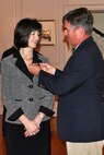 Tim Atkinson, husband of Michelle Cresswell-Atkinson, attaches the Senior Executive Service pin to her lapel during her SES induction ceremony April 18 in Harry Lee Hall at Marine Corps Base Quantico, Va. Cresswell-Atkinson serves as deputy commander for Resource Management and is the newest SES member at MCSC.