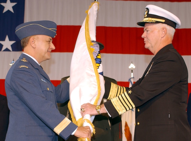 Canadian General R. R. Henault presenting the NORAD flag to Admiral Keating during the Change of Command ceremony held at Peterson, AFB, Colo. Photo by TSgt. Lawrence Holmes