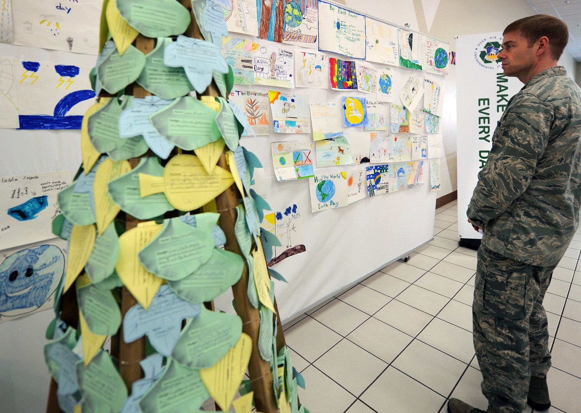 Maj. John Royal, 607th Air Operations Center executive officer, admires his son’s winning poster submitted for the Earth Day Poster Contest at Osan Air Base, Republic of Korea, April 22, 2013. The poster contest’s theme was climate change and was held to remind people to take better care of the Earth. (U.S. Air Force photo/ Staff Sgt. Sara Csurilla)