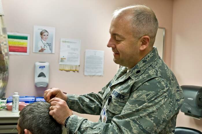 Lt. Col. (Dr.) Paul Crawford, 99th Medical Operations Squadron associate program director for Nellis Family Medicine Residency, places acupuncture needles into U.S Army Staff Sgt. Paul Kelly’s, motor transport operator from the Community Base Warrior Transition Unit in Fort Lewis, Wash., head during his acupuncture appointment April 17, 2013, at the Mike O’Callaghan Federal Medical Center, at Nellis Air Force Base, Nev. Acupuncture is a collection of procedures which involves the stimulation of points on the body using a variety of techniques like penetrating the skin with needles that are then manipulated manually or by electrical stimulation. According to the traditional Chinese medicine approach, stimulating specific acupuncture points corrects imbalances in the flow of qi through channels known as meridians. Correcting the different imbalances relieves certain types of pain and treats certain conditions like post-operative nausea, anxiety, sleep disturbances, and depression. (U.S. Air Force photo by Senior Airman Matthew Lancaster)  