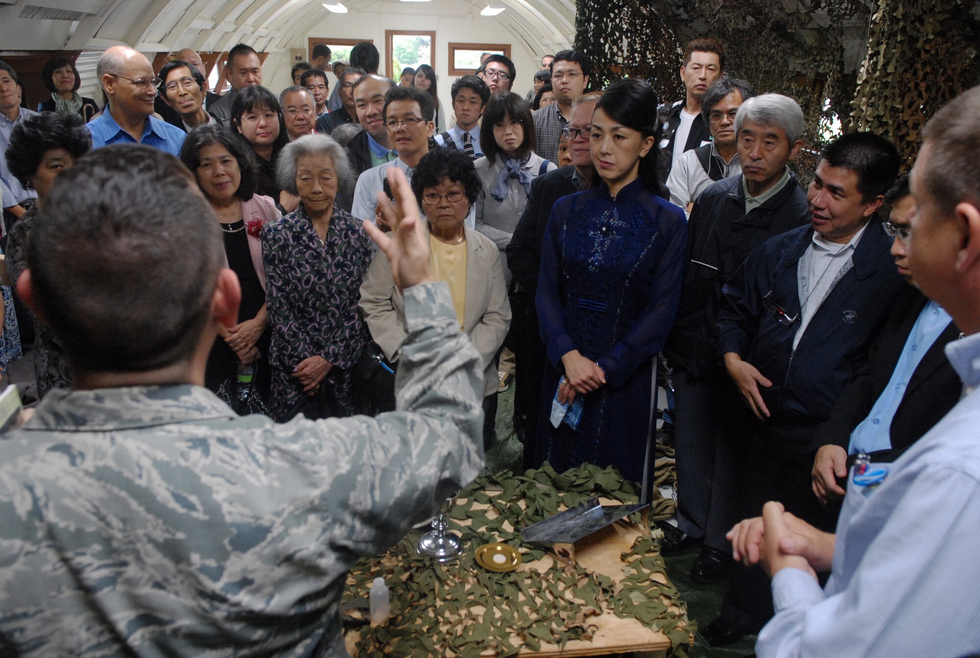 U.S. Air Force Chaplain (Capt.) Kevin Humphrey, 18th Wing chaplain, conducts a short church service for a group of Okinawan clergy in the Quonset Hut of the Air Power Park on Kadena Air Base, Japan, April 19, 2013. For the visitors, the historic building was setup similar to deployed conditions with camouflage, netting and a deployment-focused message. (U.S. Air Force photo by Staff Sgt. Lauren Snyder/Released)