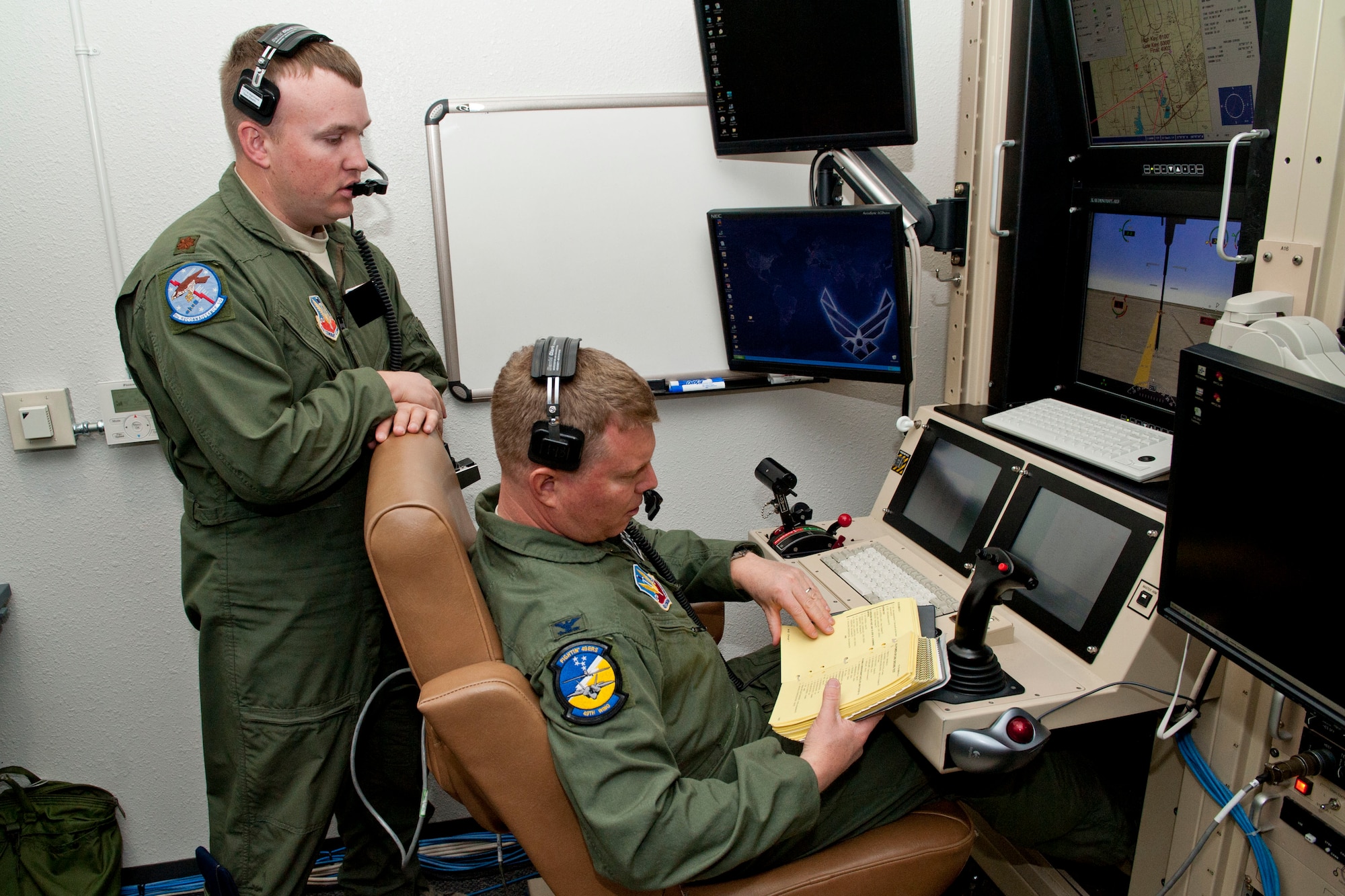 Colonel Andrew Croft, 49th Wing commander, reviews his notes before an MQ-1 Predator flight simulation at Holloman Air Force Base, N.M., April 19. According to the official MQ-1factsheet, the Predator is a medium-altitude, long-endurance, unmanned aircraft system. The MQ-1's primary mission is interdiction and conducting armed reconnaissance against critical, perishable targets. Croft is now qualified on both the MQ-1 Predator and the F-22 Raptor. (U.S. Air Force photo illustration by Airman 1st Class Colin Cates/Released) 