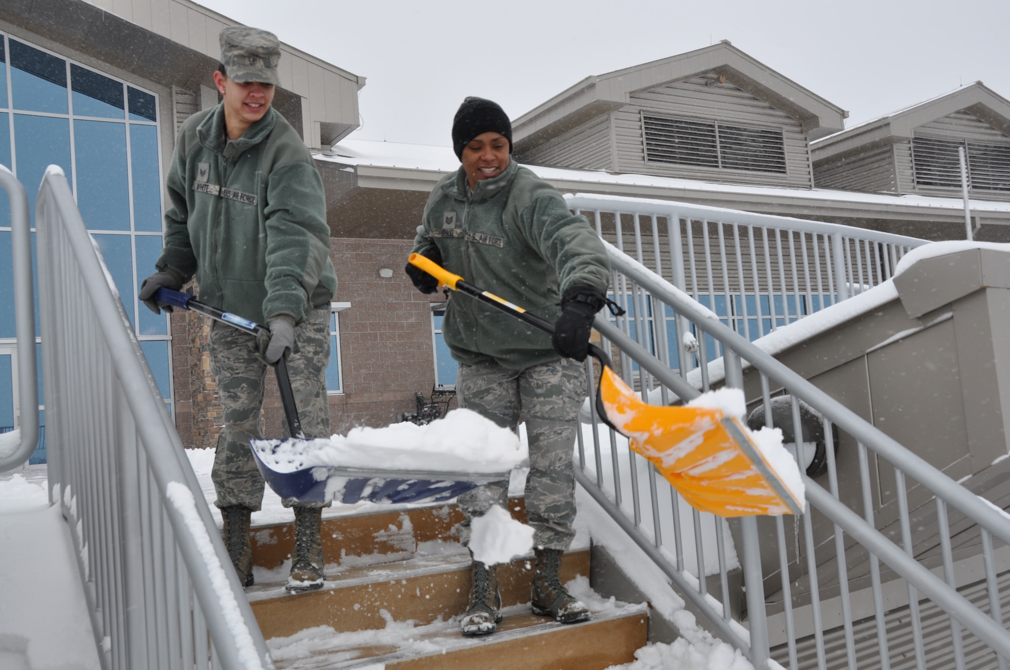 Staff Sgt. Janina White and Tech. Sgt. Taryn Shake clear snow from the steps near the patio of the Air Reserve Personnel Center here today. Buckley Air Force Base had delayed reporting due to ice and snow accumulation. (U.S. Air Force photo/Tech. Sgt. Rob Hazelett)