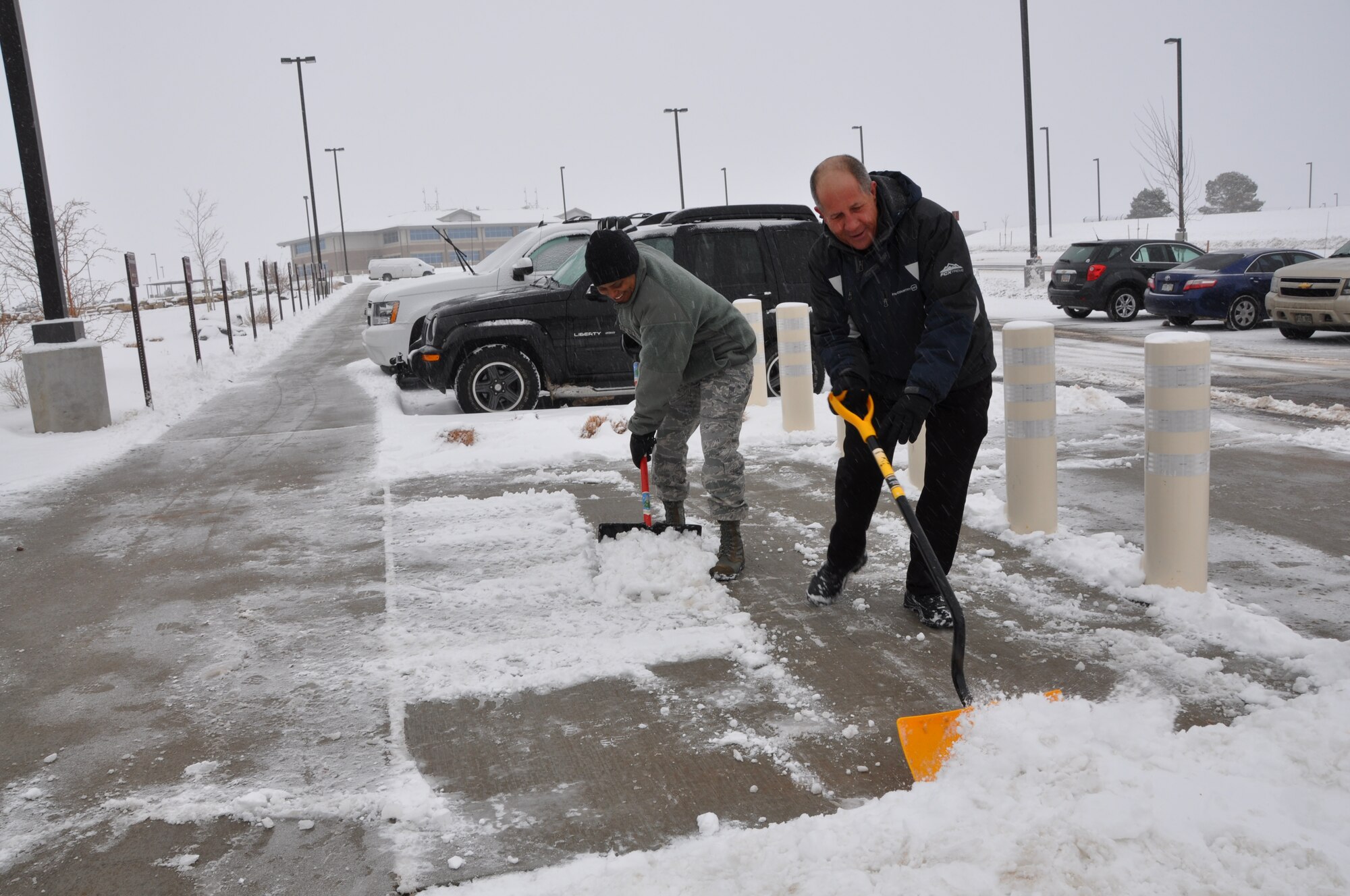 Tech. Sgt. Taryn Shake and Jon Gaines shovel snow at the entrance of the Air Reserve Personnel Center here today. Buckley Air Force Base had delayed reporting due to ice and snow accumulation. (U.S. Air Force photo/Tech. Sgt. Rob Hazelett)