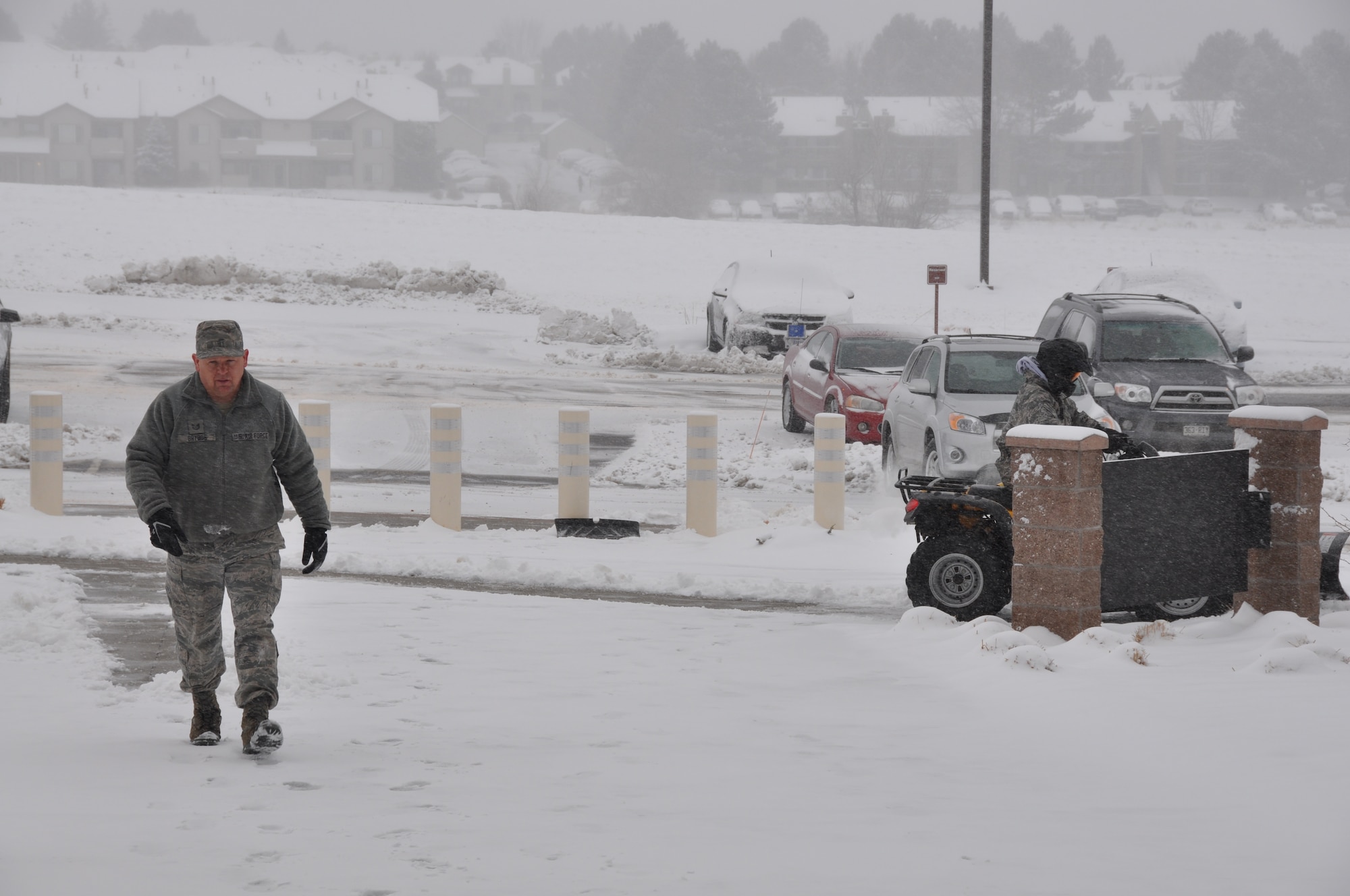Tech. Sgt. Richard Grybos, Air Reserve Personnel Center snow removal team leader, heads toward the ARPC building as Master Sgt. Javier Castro begins clearing the sidewalk here today. Buckley Air Force Base had delayed reporting due to ice and snow accumulation. (U.S. Air Force photo/Tech. Sgt. Rob Hazelett)