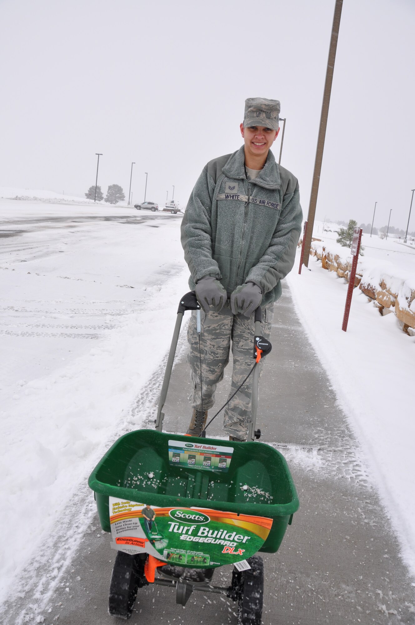 Staff Sgt. Janina White distributes ice melt on the sidewalk next to the Air Reserve Personnel Center building here today. Buckley Air Force Base had delayed reporting due to ice and snow accumulation. (U.S. Air Force photo/Tech. Sgt. Rob Hazelett)