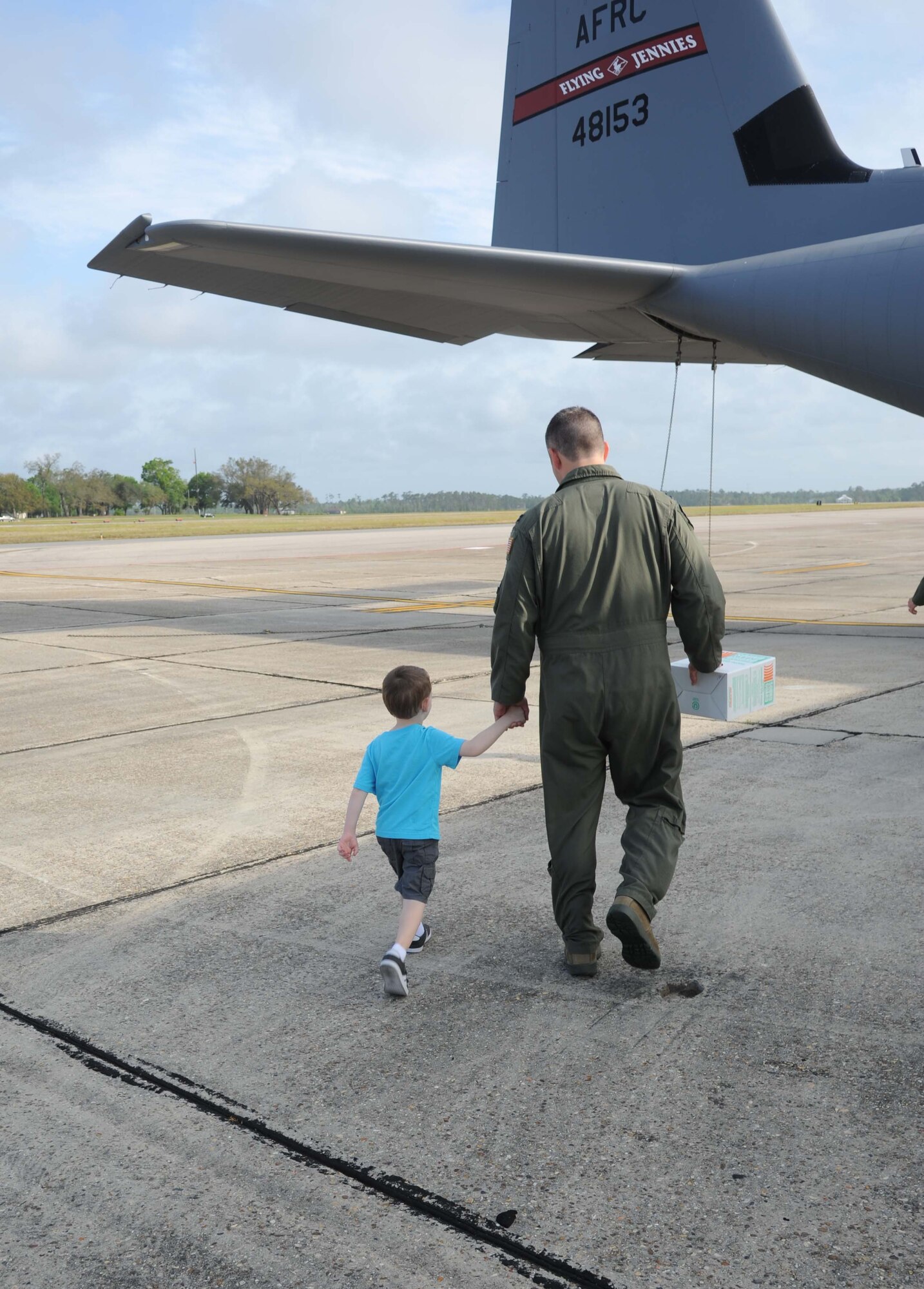 Three-year-old Ryan and his dad, Capt. Aaron Karcher, 345th Airlift Squadron, walk hand-in-hand to the back of a C-130J aircraft for a tour April 18, 2013, on the flightline at Keesler Air Force Base, Miss.  Classmates of Ryan from the child development center also toured the aircraft to learn about thing that fly.  (U.S. Air Force photo by Kemberly Groue)