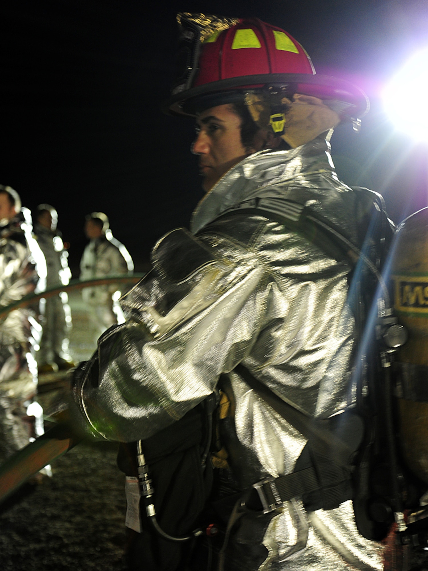 Mr. William Treat, 92nd Civil Engineer Squadron crew chief, assists "feeding hose", as other firefighters enter the training pit at Fairchild Air Force Base, Wash., April 17, 2013. Anyone entering the area is wearing about 70 pounds of protective gear while dragging fire hose. (U.S. Air Force photo by Airman 1st Class Janelle Patiño/Released)
