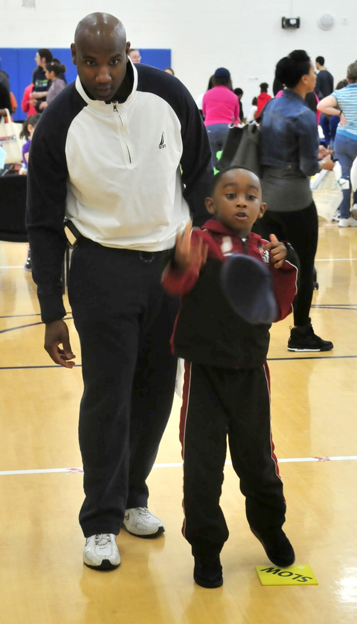 Caleb Williams tosses a bean bag toward a target as his father James watches April 20, 2013, at the youth center on Dover Air Force Base, Del. The youth center hosted a carnival to celebrate the Month of the Military Child. (U.S. Air Force photo/Tech. Sgt. Chuck Walker)