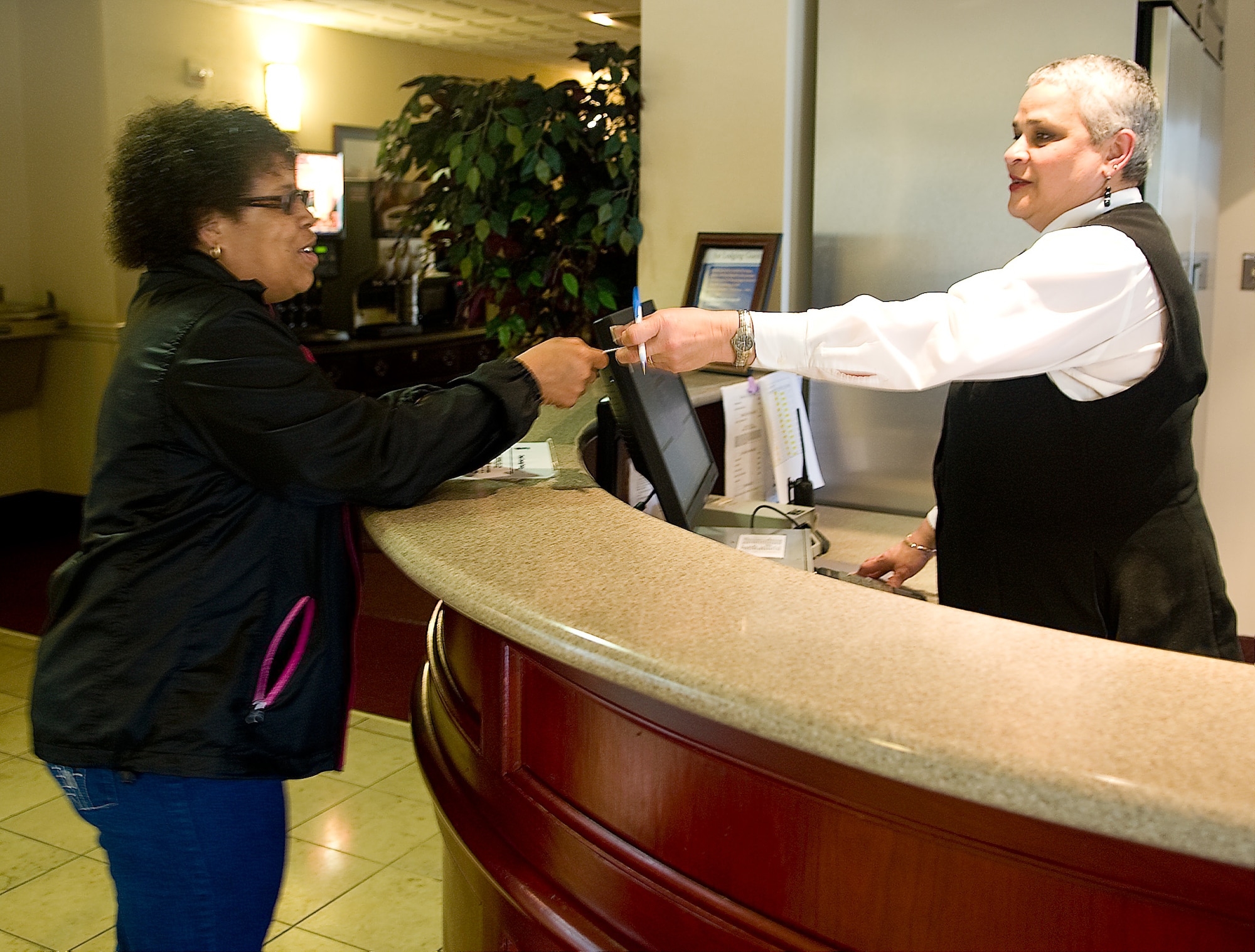 (Right) Miriam Heard, Eagles’ Rest Inn guest service representative leader, checks in a guest April 18, 2013, at the Eagles’ Rest Inn on Dover Air Force Base, Del. The lodging facility has about 60 staff members who are in charge of maintaining 240 rooms spread out over five facilities. (U.S. Air Force photo/Airman 1st Class Ashlin Federick)