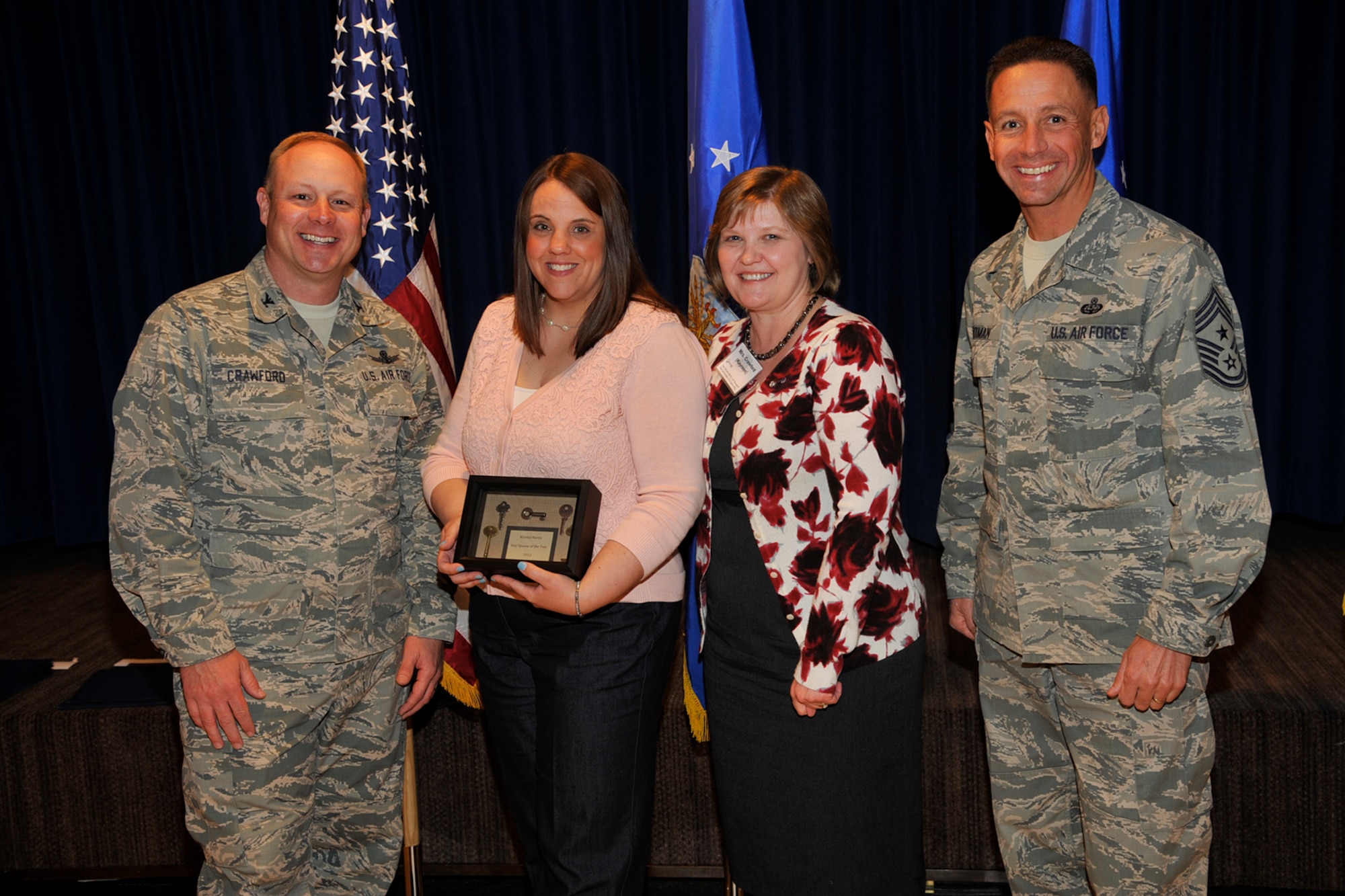 Col. Chris Crawford (left), 21st Space Wing commander, presents Krystal Harris the 2012 Key Spouse of the Year award April 15 at The Club. The Key Spouse program is an Air Force-wide volunteer program with the purpose of providing access to resources, programs and information for military spouses and family members. Also presenting the award are Kayreen Crawford, key spouse program mentor, and Chief Master Sgt. Richard Redman, 21st SW command chief. (U.S. Air Force photo/Robb Lingley)