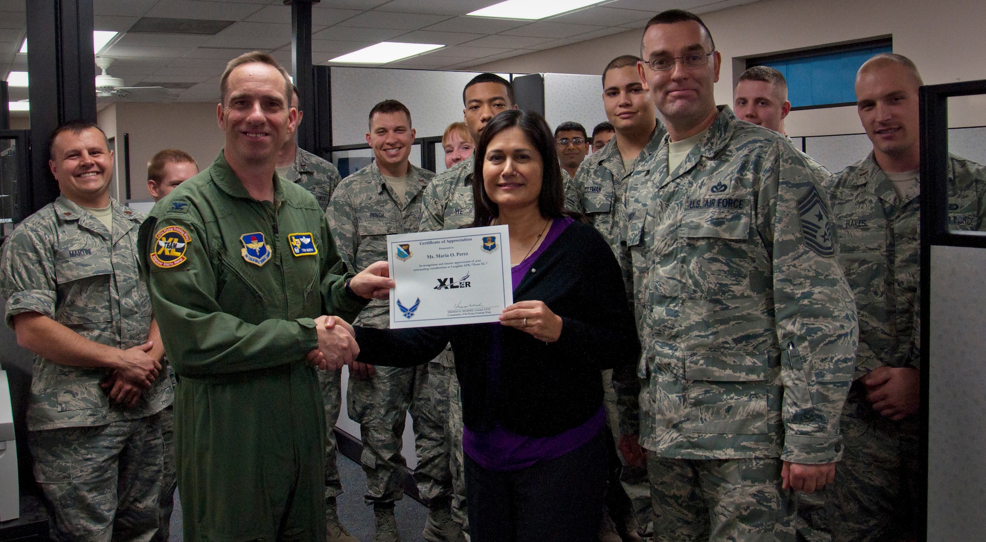 Maria Perez, 47th Comptroller Squadron non-appropriated funds financial management analyst, poses with Col. Tom Murphy, 47th Flying Training Wing commander, and Chief Master Sgt. Garry Berry, 47th FTW command chief, after being presented the XLer of the week award at Laughlin Air Force Base, Texas, April 3, 2013. The XLer is a weekly award chosen by wing leadership and given to those who consistently make outstanding contributions to Laughlin and their unit. (U.S. Air Force photo/Airman 1st Class John D. Partlow)