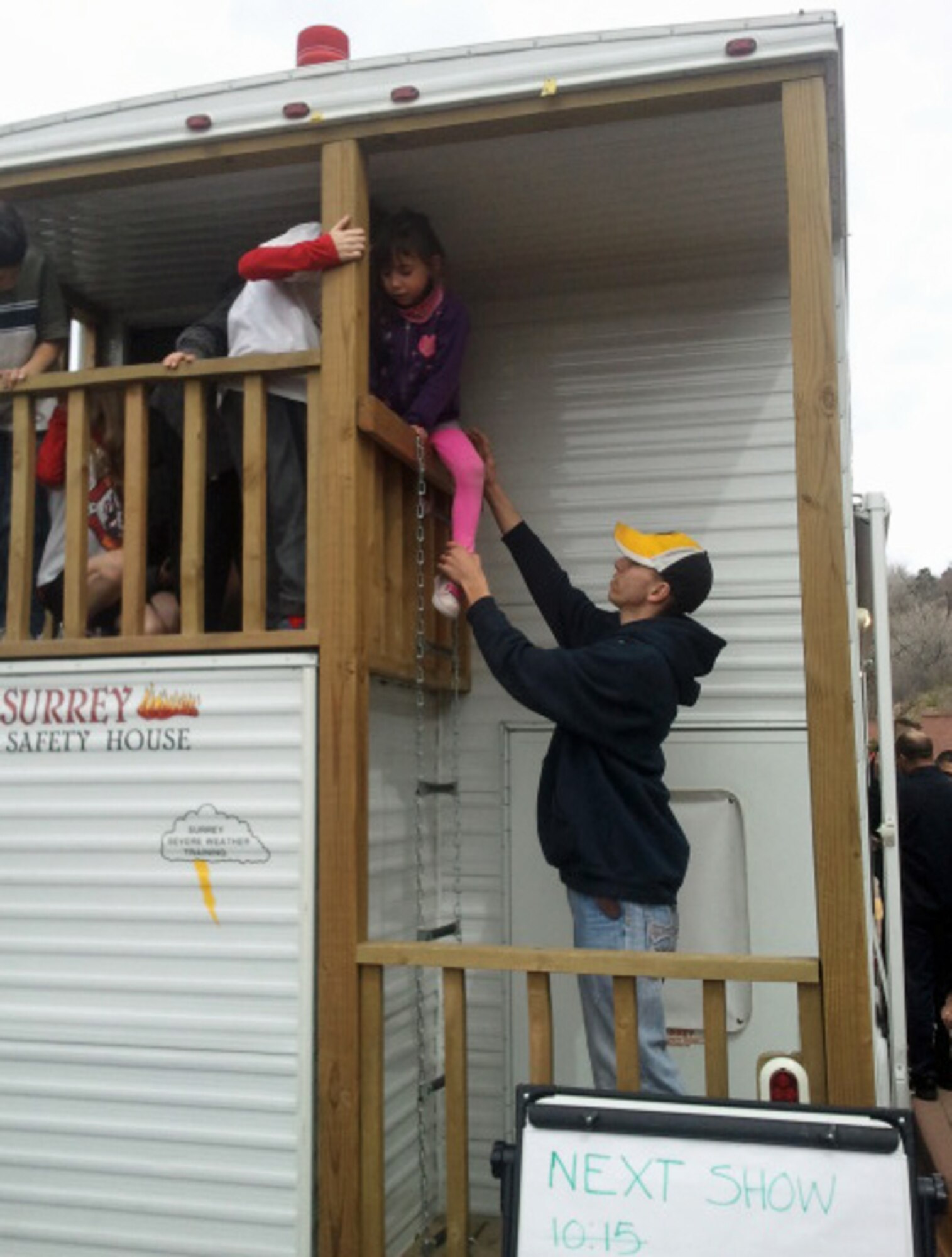 COLORADO SPRINGS, Colo. -- Airman 1st Class Brock Lillie, 21st Civil Engineer Squadron firefighter, helps Erin Brady out of the 21st CES fire safety house April 20 at Garden of the Gods visitor center. Firefighters from the 21st CES had the fire safety house on display during Earth Day activities at the park, offering fire safety tips and education. (U.S. Air Force photo/Steve Brady)