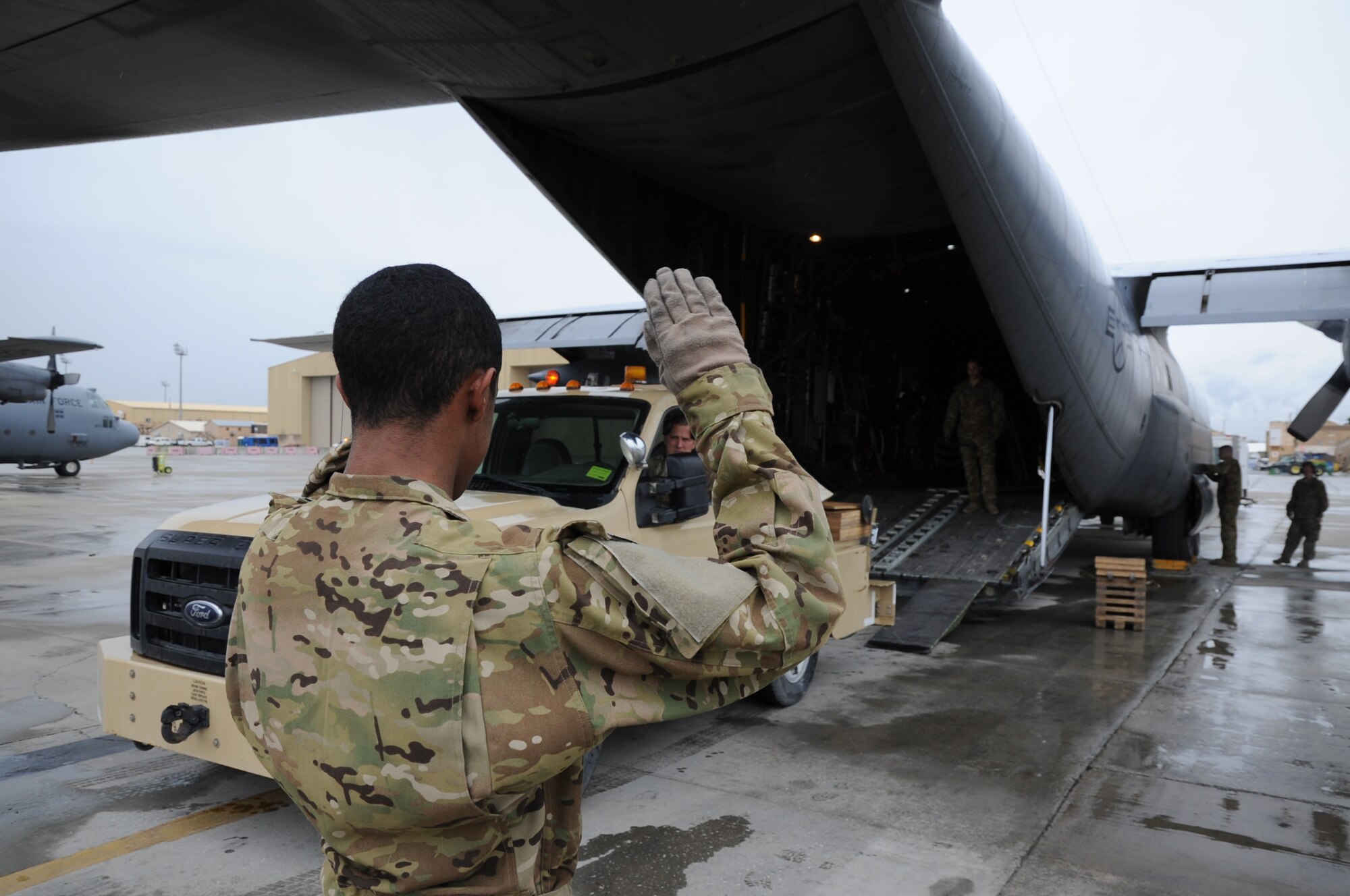 Airman 1st Class Michael Brown, 774th Expeditionary Airlift Squadron loadmaster, marshals a tractor truck onto a C-130 Hercules cargo aircraft on Bagram Airfield, Afghanistan, April 23, 2013. Loadmasters are responsible for the security and safety of all cargo on an aircraft. (U.S. Air Force photo/Staff Sgt. David Dobrydney)