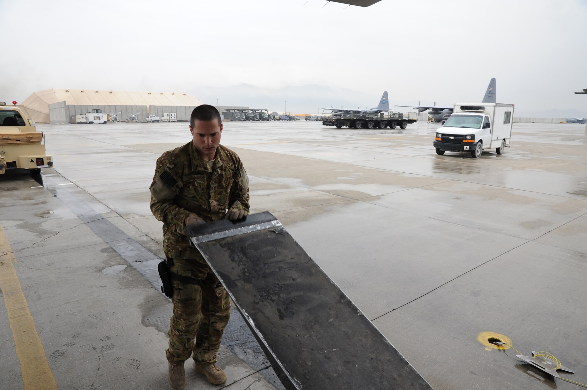 Staff Sgt. Vincent Telmanik, 774th Expeditionary Airlift Squadron loadmaster, positions a ramp so the tractor truck in the background can be loaded onto a C-130 Hercules cargo aircraft on Bagram Airfield, Afghanistan, April 23, 2013. Loadmasters supervise the loading of cargo and ensures it is secured in the aircraft. (U.S. Air Force photo/Staff Sgt. David Dobrydney)