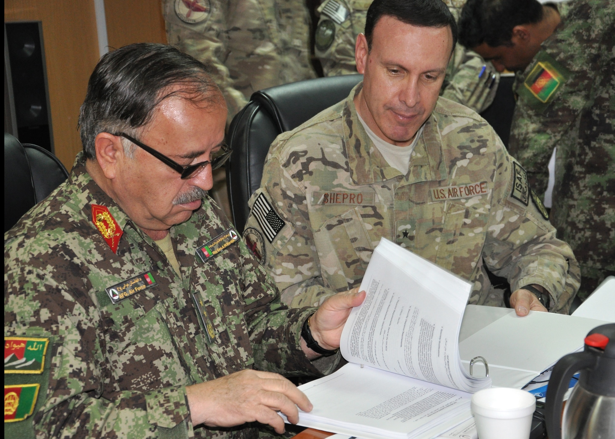 KABUL, AFGHANISTAN– Maj. Gen. Abdul Wahab Wardak, Afghan Air Force commander, looks through the newly created and adopted Afghan Air Force Military Occupation Specifications Additional Skills Identification Guide presented to him by Brig. Gen. Steven Shepro, NATO Air Training Command-Afghanistan commander, at a ceremony April 17, 2013. The AAF MOS ASI Classification Guide codifies training and knowledge standards for the AAF. This is the first document of this nature that the AAF has created and used since the Soviet occupation. (U.S. Air Force photo/Capt. Anastasia Wasem)