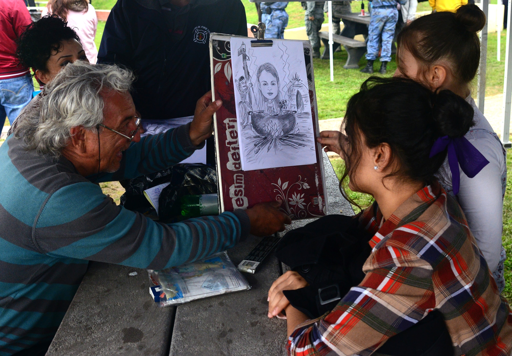 A Turkish man shows two young ladies a characture he drew of one of them during the Children’s Day Festival April 21, 2013, at Arkadas Park on Incirlik Air Base, Turkey. The event was hosted by the Turkish air force 10th Tanker Base Command and was open to all members of Team Incirlik. The event featured activity booths, games and performances designed to honor children and celebrate cultures coming together.  (U.S. Air Force photo by Staff Sgt. Eric Summers Jr./Released)
