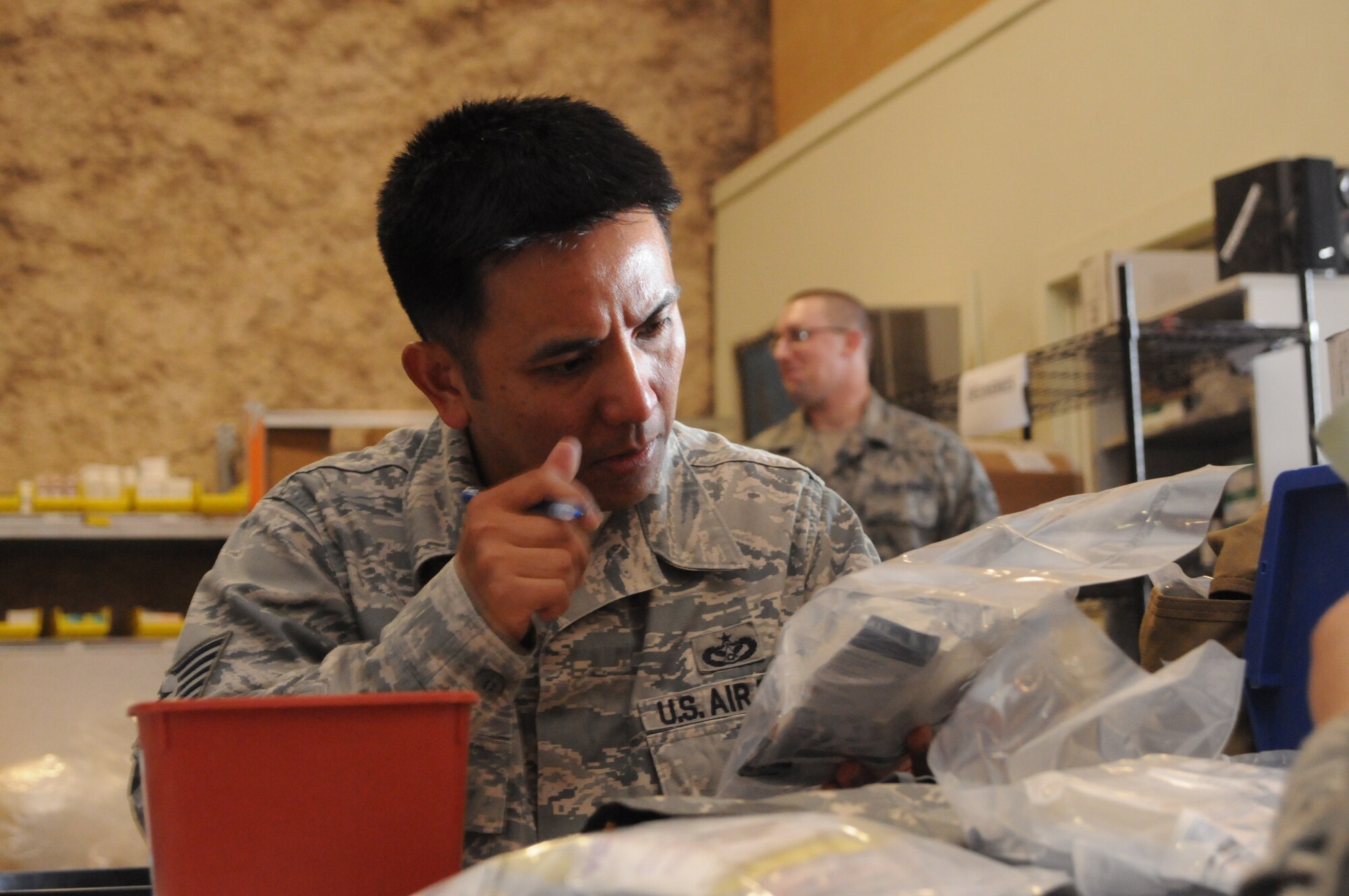 SOUTHWEST ASIA -- Tech. Sgt. Ernesto Racoma double checks the labeling on a component of an individual first aid kit. Thirty three volunteers crowded into the 379th Expeditionary Medical Group Medical Logistics Warehouse for four hours April 19 to recertify up to 1,500 IFAKs used by forward operating bases of all services across the U.S. Central Command's area of responsibility. These missions are held monthly by the 379th EMDG, one of only two locations in the AOR capable of recertifying IFAKs. (U.S. Air Force photo/Master Sgt. Christian Michael)