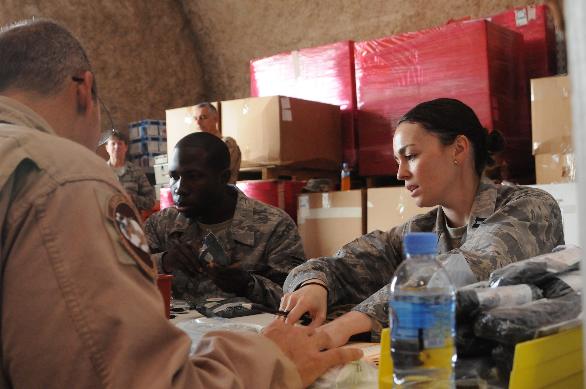 SOUTHWEST ASIA -- Tech. Sgt. Christopher Wild, Staff Sgt. Willet Smith and Capt. Danielle Merritt recertify individual first aid kits. Thirty three volunteers crowded into the 379th Expeditionary Medical Group Medical Logistics Warehouse for four hours April 19 to recertify up to 1,500 IFAKs used by forward operating bases of all services across the U.S. Central Command's area of responsibility. These missions are held monthly by the 379th EMDG, one of only two locations in the AOR capable of recertifying IFAKs. (U.S. Air Force photo/Master Sgt. Christian Michael)