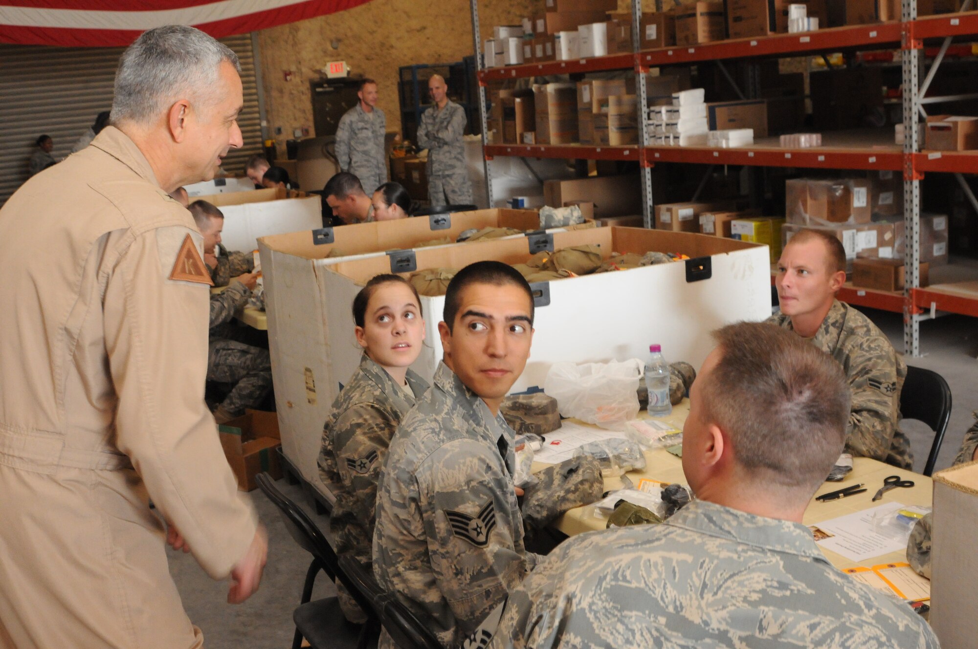 SOUTHWEST ASIA -- Brig. Gen. Roger Watkins, 379th Air Expeditionary Wing commander speaks with some of the thirty three volunteers who crowded into the 379th EMDG Medical Logistics Warehouse for four hours April 19. They recertified up to 1,500 individual first aid kits used by forward operating bases of all services across the U.S. Central Command's area of responsibility. These missions are held monthly by the 379th EMDG, one of only two locations in the AOR capable of recertifying IFAKs. (U.S. Air Force photo/Master Sgt. Christian Michael)