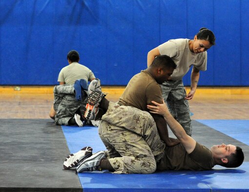 Tech. Sgt. Armida Dicicco, 386th Air Expeditionary Wing, Check Six instructor, teaches Cpl. Ricardo Rampersad (top) and Sgt. Beau Long, from the Canadian Forces the scissor sweep technique at the 386th Air Expeditionary Wing, Southwest Asia Apr 22, 2013. Rampersad and Long are the first non-Airman to receive AFCENT Check Six combatives training at ‘The Rock’. (U.S. Air Force photo by Senior Master Sgt. George Thompson)