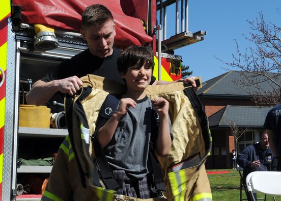 Airman 1st Class Jacob Dietmeyer, 100th Civil Engineer Squadron firefighter from Gurnee, Ill., assists Jack Peak, 8, son of Lt. Col. John Peak, 67th Special Operations Squadron director of staff, as he tries on a structural firefighting ensemble during the RAF Mildenhall Child Development Center and Airmen and Family Readiness Center Spring Fest and Child Find event April 20, 2013, at RAF Mildenhall, England. With spring weather finally rolling in, Team Mildenhall children and parents got out and enjoyed the activities of the event. (U.S. Air Force photos by Staff Sgt. Tabitha M. Lee/Released)