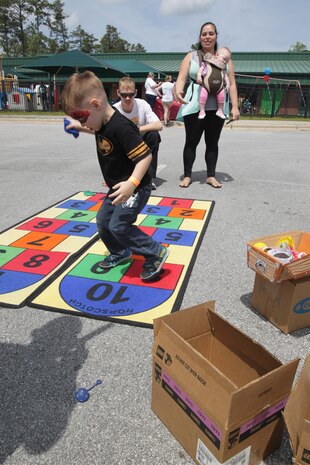 A Marine teaches his child how to play hopscotch to celebrate the Month of the Military Child during a block party at the Child Development Center aboard Marine Corps Air Station New River, April 13. The Children, Youth and Teen Program hosted the party to inform the children about what their parents do aboard the air station.
