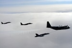 A CF-18 Hornet tops up its tanks from a CC-130T Hercules, both from the Canadian North American Aerospace Defense Command Region, while two F-15 Eagles from Elmendorf Air Force Base, Alaska, fly nearby. The aircraft were in the Canadian north in March 2007 to practice joint long-range detection missions and other NORAD procedures.