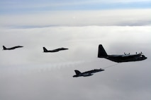 A CF-18 Hornet tops up its tanks from a CC-130T Hercules, both from the Canadian North American Aerospace Defense Command Region, while two F-15 Eagles from Elmendorf Air Force Base, Alaska, fly nearby. The aircraft were in the Canadian north in March 2007 to practice joint long-range detection missions and other NORAD procedures.