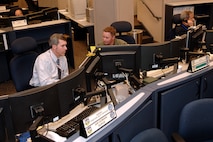Inside the North American Aerospace Defense Command and U.S. Northern Command command center at Peterson Air Force Base, Colo., NORAD Air Director Bill Glover, left, and NORAD fighter duty officer Air Force Lt. Col. Jim Robinson, center, monitor missile, space and air events in the NORAD area of responsibility. NORAD has about 25 fighter duty officers, who rotate six-and-a-half-hour shifts in the command center.
Photo by Sgt. 1st Class Gail Braymen 