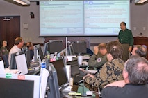 Members of the Joint Interagency Coordination Group at the North American Aerospace Defense Command and U.S. Northern Command discuss how best to respond to scenarios in the Vigilant Shield '08 exercise at the commands' headquarters at Peterson Air Force Base, Colo. The exercise provides local, state, tribal, interagency, Department of Defense and non-governmental organizations and agencies involved in homeland security and homeland defense the opportunity to participate in a full range of exercise scenarios that will better prepare participants to prevent and respond to national crises. Photo by Petty Officer 2nd Class Jhomil Bansil 