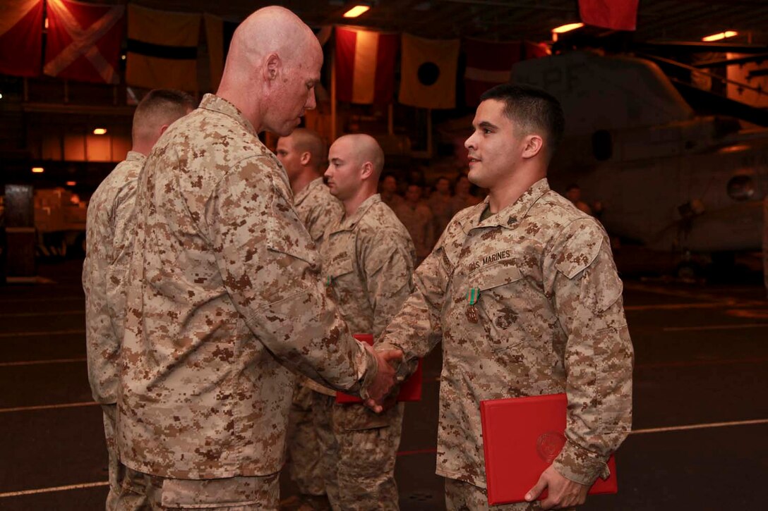 Corporal Scott L. Quesenberry, radio operator, Marine Medium Helicopter Squadron 364 (Rein.), 15th Marine Expeditionary Unit, shakes hands with Lt. Col. John M. Field, his commanding officer, after he received a Navy and Marine Corps Achievement Medal during a ceremony held in the hangar bay of USS Peleliu, April 14. The 15th MEU is deployed as part of the Peleliu Amphibious Ready Group and is comprised of approximately 2,400 Marines and sailors. Together with Amphibious Squadron Three, they provide a forward-deployed, flexible sea-based Marine Air Ground Task Force capable of conducting a wide variety of operations ranging from humanitarian aid to combat. Quesenberry, 21, is from Greensboro, N.C. (U.S. Marine Corps photo by Cpl. John Robbart III/Released)