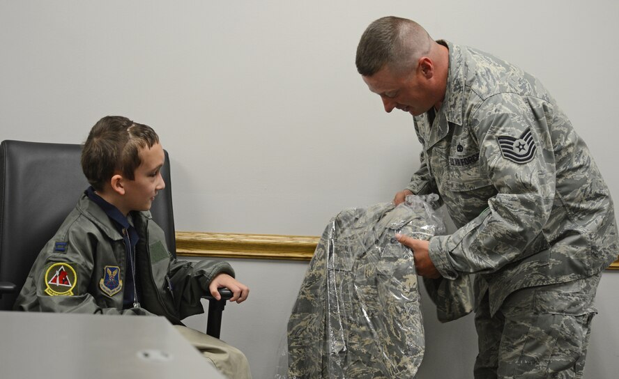 Tech. Sgt. Mark Haines, 2nd Aircraft Maintenance Squadron crew chief, presents Hunter Tomlin, 8, with a personalized Airman Battle Uniform on Barksdale Air Force Base, La, April 24, 2013. The Marshall, Texas, native was made a B-52H Stratofortress honorary crew chief. (U.S. Air Force photo/Senior Airman Micaiah Anthony)