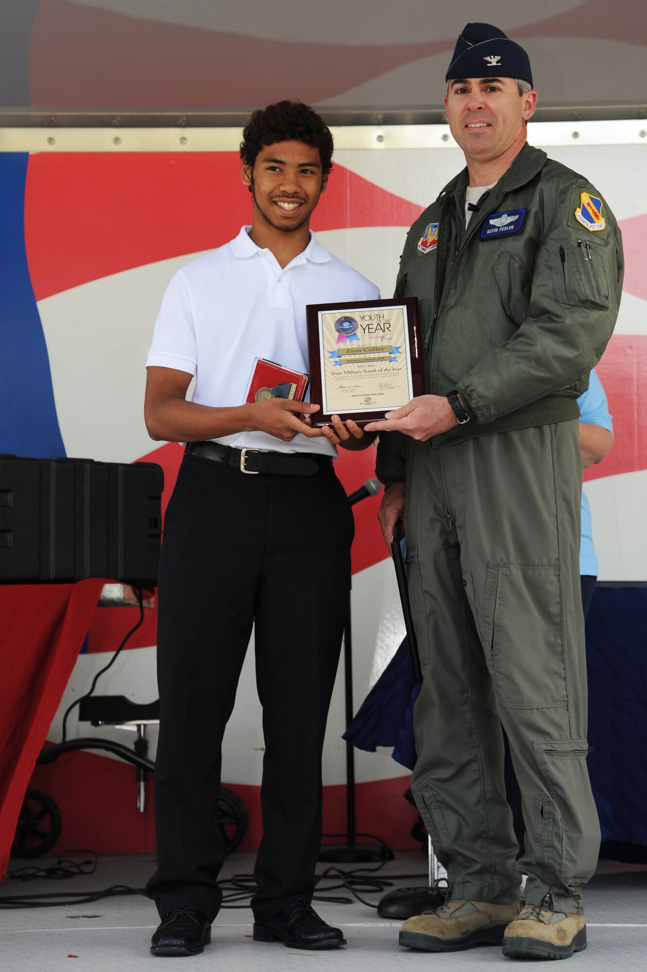 U.S. Air Force Col. Kevin Fesler, 4th Fighter Wing vice commander, presents Zion Culley, son of Senior Master Sgt. Christopher Culley, 4th Operation Support Squadron aircrew flight equipment superintendent, with the State Military Youth of the Year award at the Youth Center on Seymour Johnson Air Force Base, N.C., April 20, 2013.  By winning the state competition, Culley will compete in the South East Regionals in Atlanta, June 17-20, 2013.  (U.S. Air Force photo by Airman 1st Class Brittain Crolley/Released)