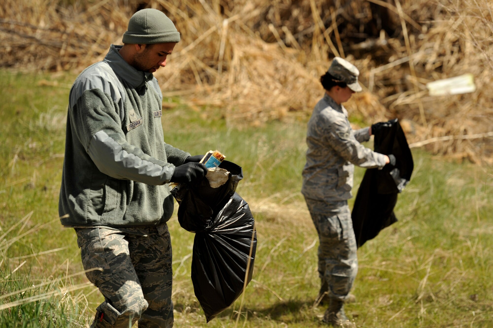Airman 1st Class Justyn Freeman, a combat photojournalist, and Senior Airman Barbara Aguirre, a combat broadcast journalist, both with the 2nd Combat Camera Squadron, clean up the duck pond running trail area as part of an Earth Day event at Hill Air Force Base, Utah, April 22, 2013. Fifteen Airmen collected more than 10 large bags of trash from the popular running trail as a way to help clean up the base and help protect the environment. (U.S. Air Force photo/Staff Sgt. Renae Saylock)