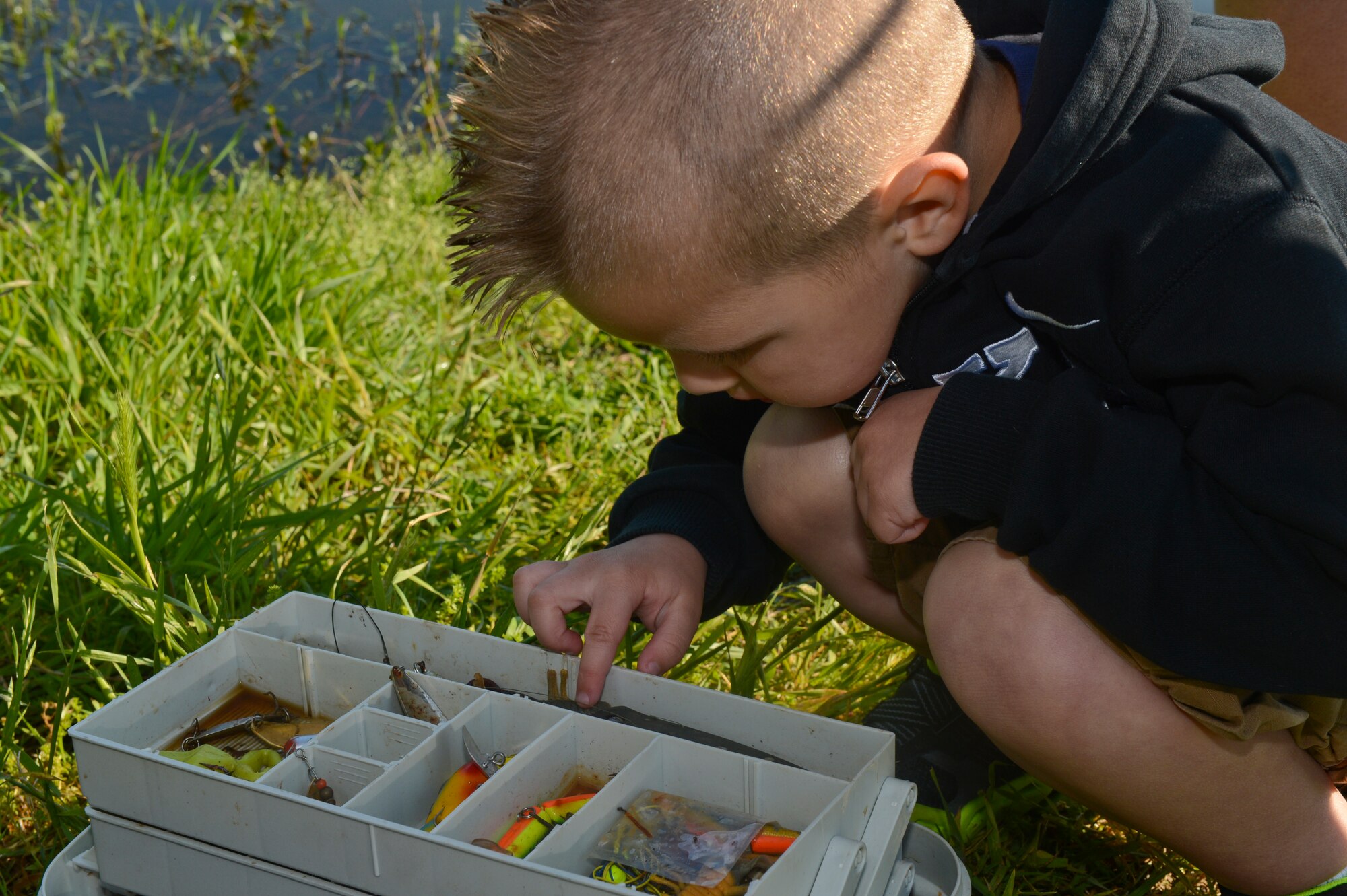 A child participating in the 8th annual Kids Fish event searches for a fishing lure on Barksdale Air Force Base, La., April 20, 2013. Earlier that morning he caught his first fish. Kids Fish was held to increase recreational outings for military families with base access. (U.S. Air Force photo/Senior Airman Micaiah Anthony)
