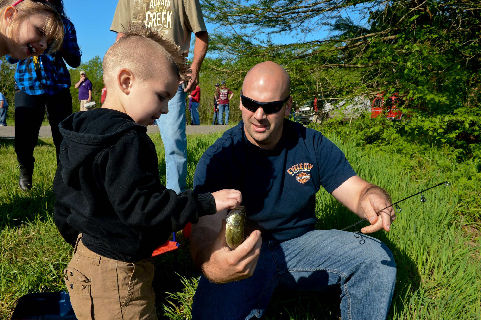 Capt. Michael Plourde, 96th Bomb Squadron, hands his son a fish during the 8th annual Kids Fish event on Barksdale Air Force Base, La., April 20, 2013. Prizes were awarded to the children who caught the most, largest and smallest fish, along with the child with the coolest hat. (U.S. Air Force photo/Senior Airman Micaiah Anthony) 
