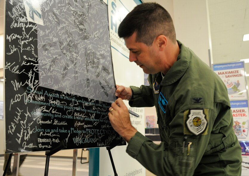 Col. Andrew Gebara, 2nd Bomb Wing commander, signs the Sexual Assault Prevention and Response pledge board at the Exchange on Barksdale Air Force Base, La., April 23, 2013. April is Sexual Assault Awareness month. Since the beginning of the month, the Sexual Assault Response Coordinator office has provided a board for members of Team Barksdale to sign pledging to be vigilant and aware of sexual violence. (U.S. Air Force photo/Airman 1st Class Andrew Moua)
