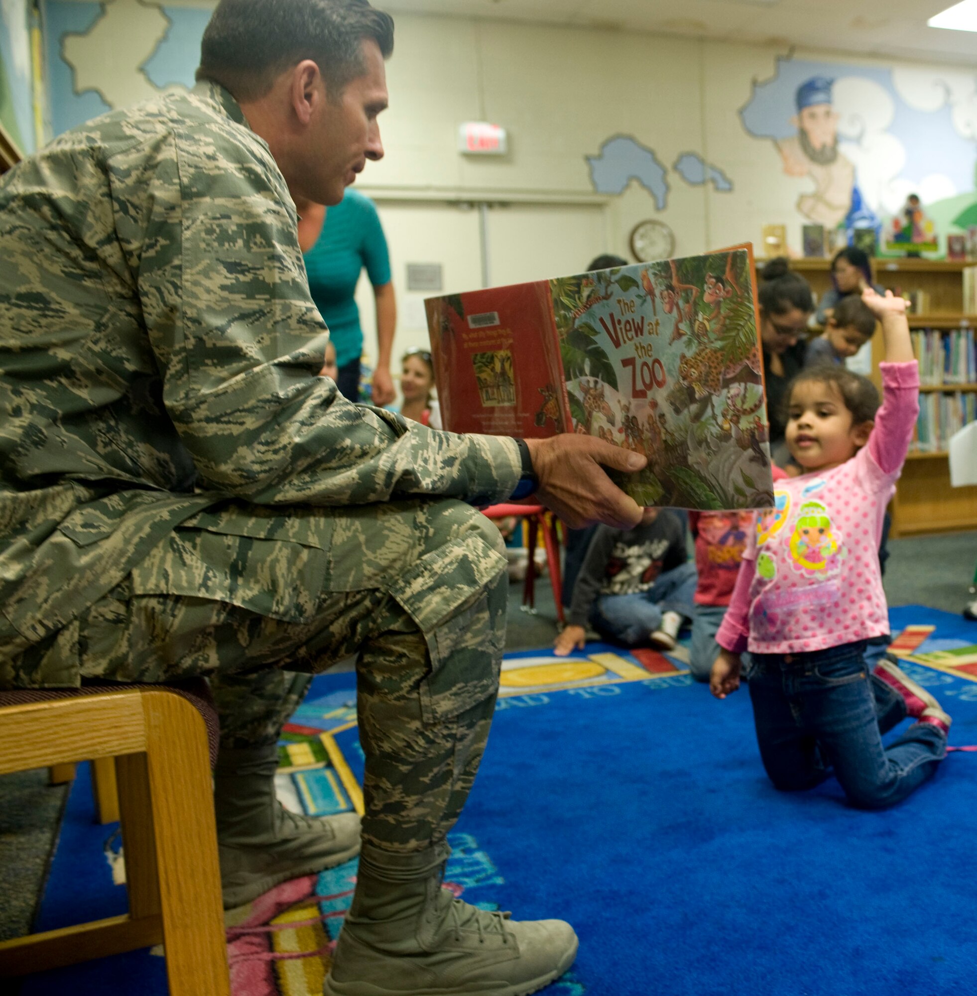 Approximately 15 children and their mothers gather to listen to 99th Air Base Wing Commander Col. Barry Cornish read from picture books as part of child abuse awareness and prevention month, April 17, 2013 at the Nellis Air Force Base, Nev., library. For further information on programs which can bolster communication and mental health for the whole family, contact the Nellis Family Advocacy Program at 653-3880, or through the BOUNCE page on the Nellis website. (U.S. Air Force photo/Benjamin Newell)