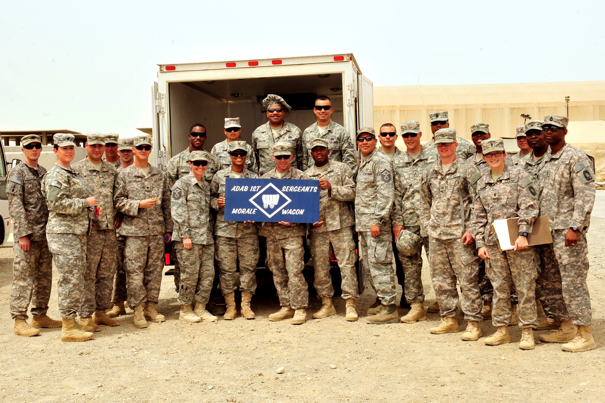 U.S. Air Force and Army first sergeants pose for a group photo with Headquarters and Headquarters Battery 1-62 Air Defense Artillery Soldiers during the monthly ADAB First Sergeants Morale Wagon at an undisclosed location in Southwest Asia April 5, 2013.  The first sergeants prepared and served more than 300 hotdogs, cookies, snacks and drinks to Airmen and Soldiers. The morale wagon gives first sergeants an additional way to get out amongst servicemembers, talk with them and raise their morale. (U.S. Air Force photo by Tech. Sgt. Christina M. Styer)