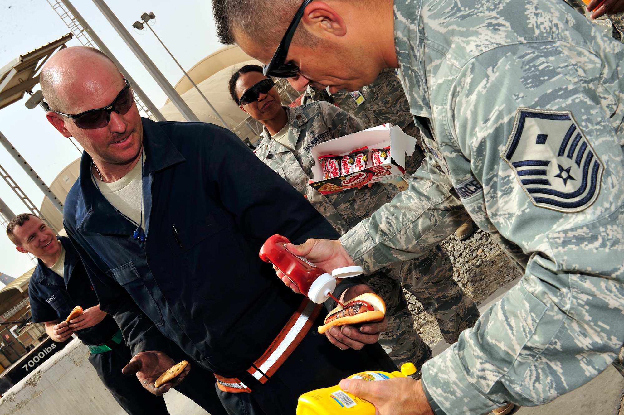 U.S. Air Force Master Sgt. Michael Garcia, 380th Expeditionary Communications Squadron first sergeant, deployed from Royal Air Force Mildenhall, England, serves an Airman assigned to the 380th Expeditionary Aircraft Maintenance Squadron at the ADAB First Sergeant's Morale Wagon at an undisclosed location in Southwest Asia April 5, 2013. Once a month the first sergeants serve hotdogs, cookies, snacks and drinks to Airmen and Soldiers around base and on the flightline in order to help raise morale. The first sergeants prepared and served more than 300 hotdogs during this event and interacted with servicemembers for more than four hours. (U.S. Air Force photo by Tech. Sgt. Christina M. Styer)