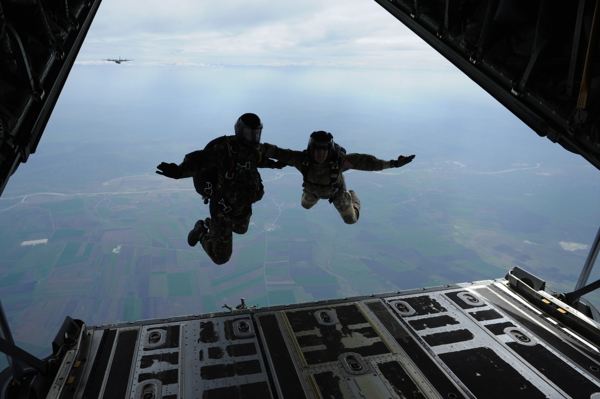 A Romanian and Air Force paratrooper jump out of the back end of a C-130J Super Hercules during Exercise Carpathian Spring, April 16, 2013, Bucharest, Romania. The exercise was designed for aircrew to receive upgrade training as well as building partnership capacity with Romanians. (U.S. Air Force photo/Airman 1st Class Hailey Haux)