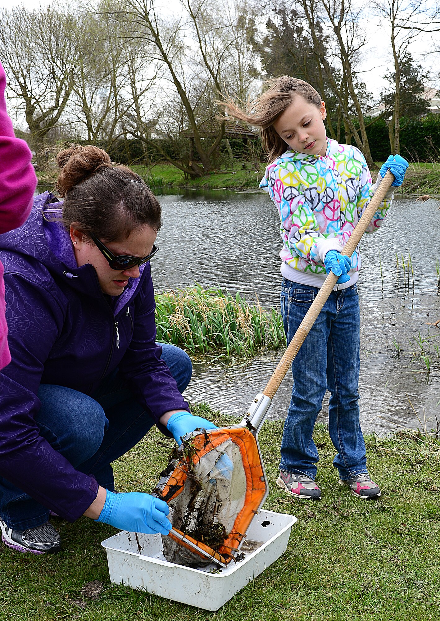 ROYAL AIR FORCE LAKENHEATH, England—Krisa Engel (left), Department of Defense third grade teacher, helps Alyssa Ransted, daughter of Tech. Sgt. Steven Ransted, 100th Maintenance Squadron, RAF Mildenhall, empty her nature net into a bucket at Defenders Park during a pond dipping activity for Earth Week, April 18, 2013. Earth Day, which is on April 22, is an annual event held worldwide, showing support for environmental protection. (U.S. Air Force photo by Staff Sgt. Stephanie Mancha)