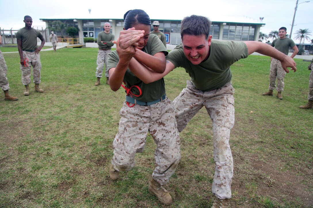 Cpl. Kayla E. Morales, left, demonstrates how to properly use a takedown technique with Lance Cpl. Christopher R. Hutchingson at Camp Schwab April 15 during security augmentation force training. The training included baton fundamentals, oleoresin capsicum, or OC, spray certification, escalation of force and mechanical advantage control hold techniques, which are defensive hand-to-hand techniques. Morales and Hutchingson are currently assigned to Camp Hansen’s SAF. Photo by Lance Cpl. Henry J. Antenor