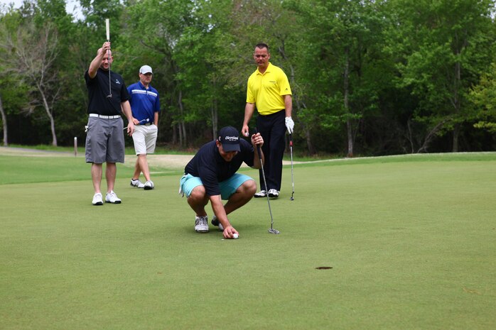 A team out of the 23 teams at the Marine Corps Air Station New River Marine Corps Community Services Spring Golf Tournament watches as their teammate prepares to putt his golf ball at Bear Trails Golf Course in Jacksonville, N.C., April 19.